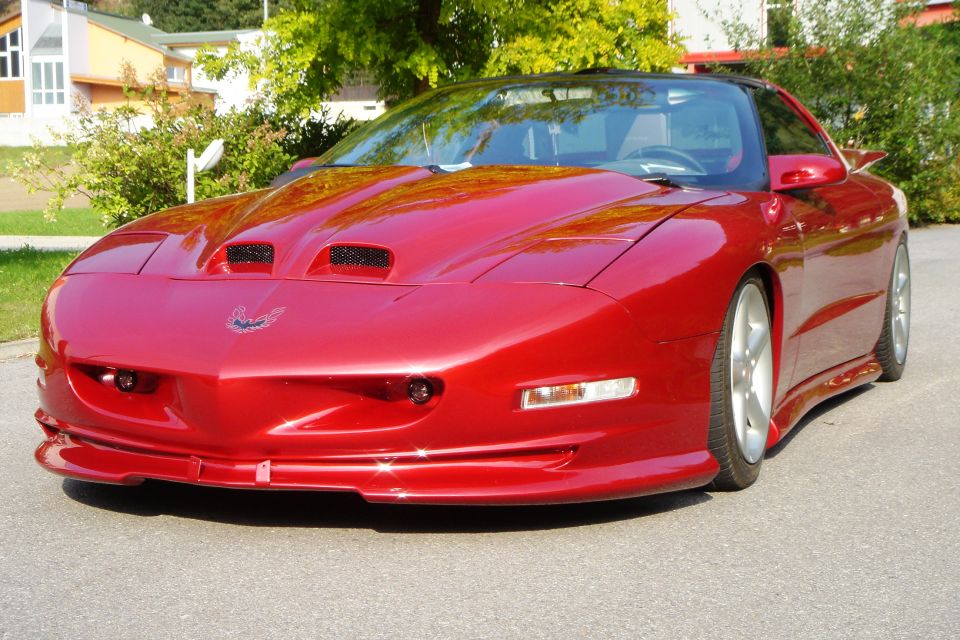 Red Pontiac Firebird coupe, front 3/4 view with hood scoops and alloy wheels