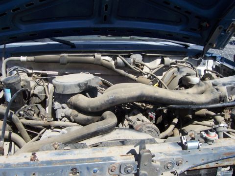1991 Ford Bronco - The engine bay of a vehicle is shown with various mechanical parts and hoses.