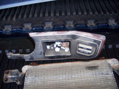 1991 Ford Bronco - This photo shows a 4x4 shifter trim piece and an oil cooler, likely parts from a vehicle.