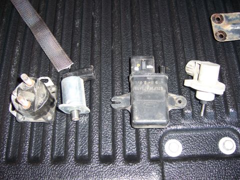 1991 Ford Bronco - Various automotive sensors are displayed on a black, ribbed surface, with a grey strap visible.