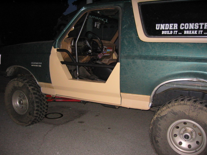 1991 Ford Bronco side view, door removed, roll cage installed, "UNDER CONSTRUCTION" sticker on window