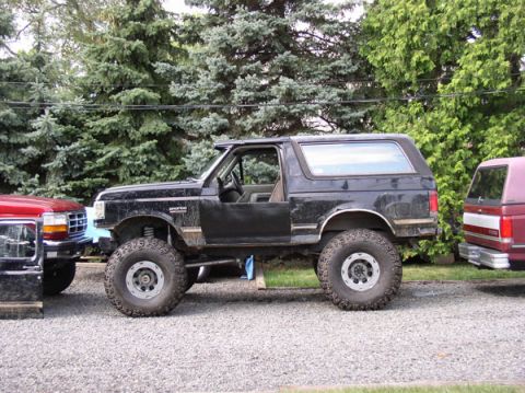 1991 Ford Bronco - This black Ford Bronco has been modified with a lift kit and oversized tires, parked next to another Ford vehicle.
