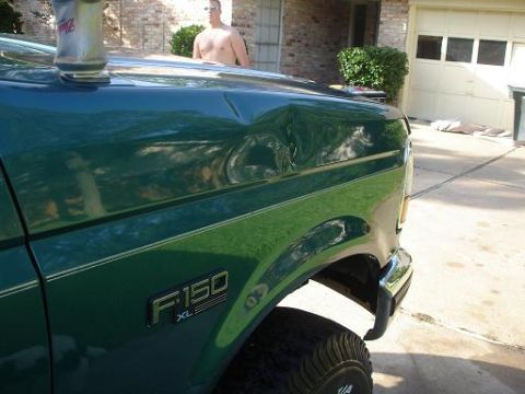 1996 Ford F-150 - A green Ford F-150 XL with a dented hood is parked in a driveway. A man stands in the background.