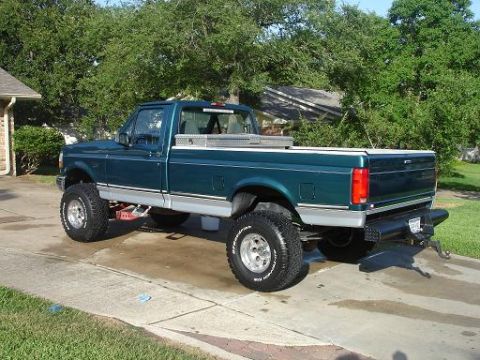 1996 Ford F-150 - This lifted green Ford F-150 pickup truck is viewed from the rear three-quarter angle on a sunny day.