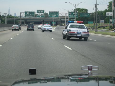 1991 Ford LTD Crown Victoria - North Haven Police cruiser with lightbar drives down a highway past overhead signs for the Lincoln Tunnel and NJ Turnpike.
