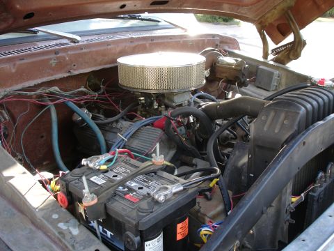 1977 Ford F-150 - The engine bay of a brown 1977 Ford F-150 shows dual batteries and a large air filter.