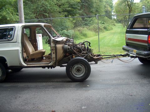 1988 Ford Bronco - Stripped white square-body Chevy/GMC truck cab with no front clip, hood or fenders, exposing the engine, frame rails and tan bench interior…