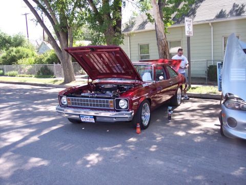 1972 Ford Ranchero - A maroon sedan is parked with its hood open, alongside another vehicle at an outdoor event.