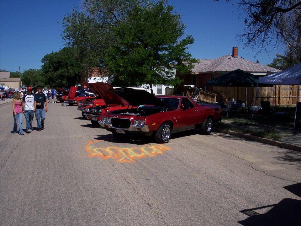 Red 1972 Ford Ranchero parked on street with hood up, other cars lined up