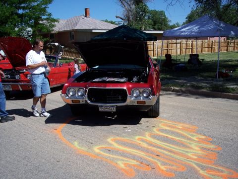 1972 Ford Ranchero - A red 1970s Ford Ranchero is displayed with its hood open at an outdoor car show, with chalk art on the asphalt in front of it.