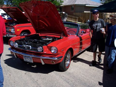 1972 Ford Ranchero - A red 1965 Ford Mustang convertible is displayed with its hood open at an outdoor car show.