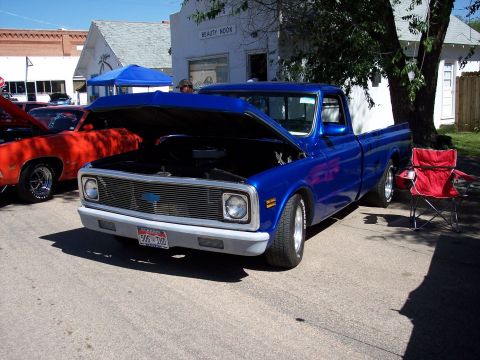 1972 Ford Ranchero - A blue pickup truck, possibly a 1970 Chevrolet C/K, is displayed with its hood open at a car show.