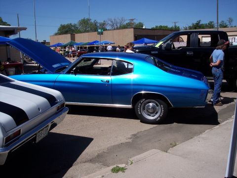 1972 Ford Ranchero - A bright blue coupe, possibly a 1972 Chevrolet Chevelle, is displayed with its hood open at an outdoor car show.