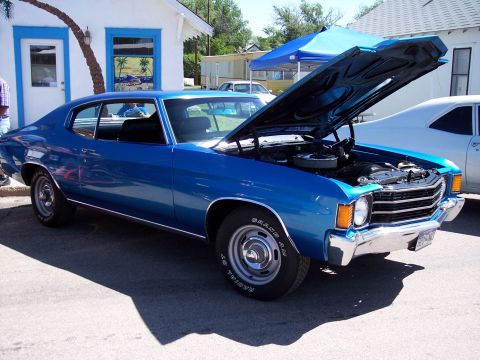 1972 Ford Ranchero - A blue coupe with its hood open is parked outside a building with a blue trim window.