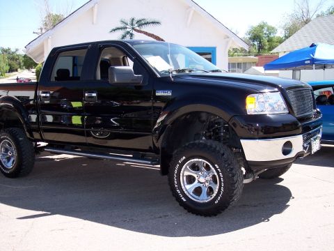1972 Ford Ranchero - This black Ford F-150 pickup truck is parked outside a building with a palm tree mural.