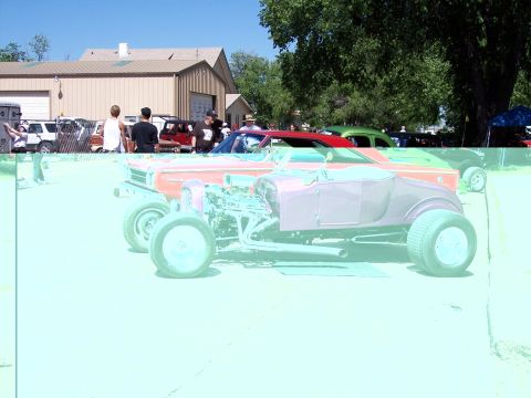 1972 Ford Ranchero - A custom hot rod with a prominent engine and wide rear tires is displayed at an outdoor car show.