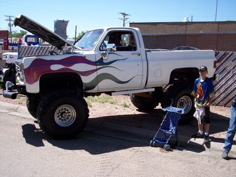 1972 Ford Ranchero - This lifted pickup truck features custom flame graphics and an open hood, with a young boy standing nearby.