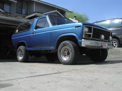 1981 Ford Bronco - A blue 1981 Ford Bronco is parked in a driveway, showing its front three-quarter view and aftermarket wheels.