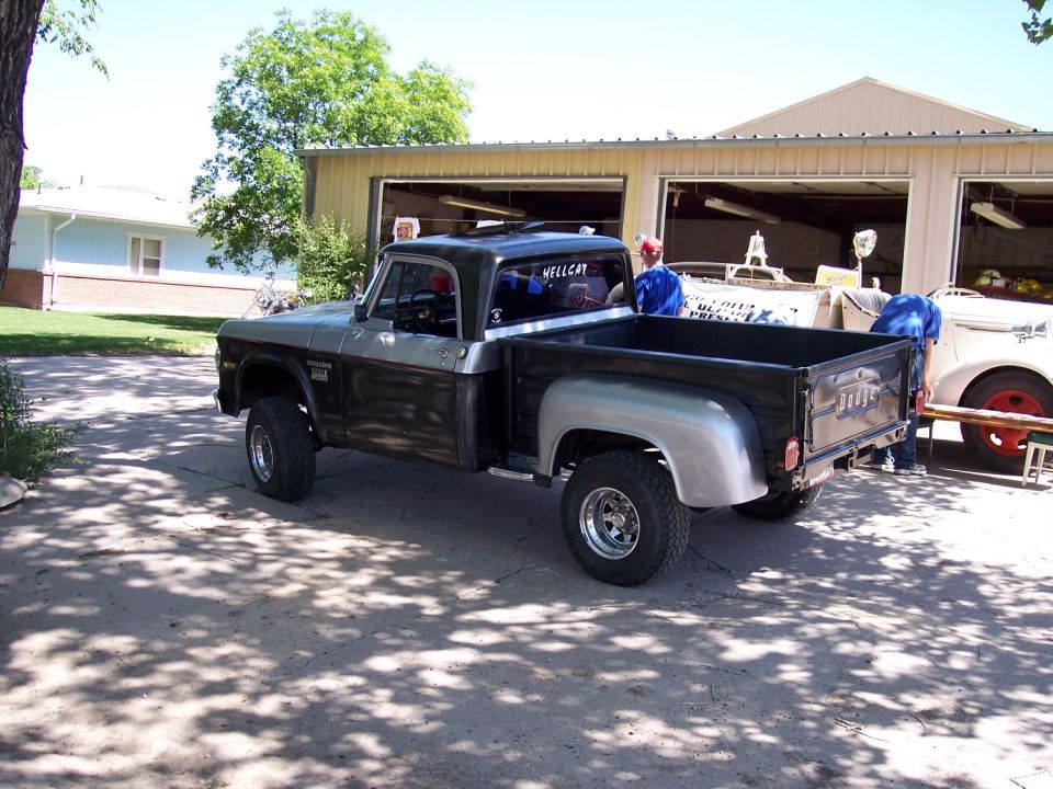 Two-tone pickup truck with silver fenders and black bed, parked in a driveway