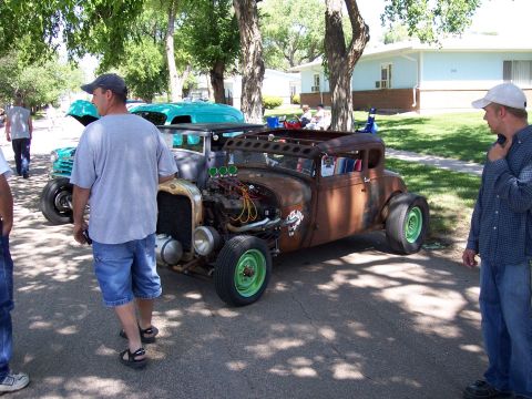 1972 Ford Ranchero - A custom-built rat rod with a rusty patina and bright green wheels is displayed at a car show.