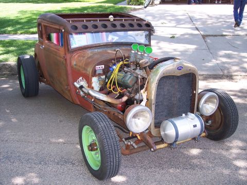 1972 Ford Ranchero - A heavily modified vintage car, commonly known as a rat rod, is parked on a street with its engine exposed.