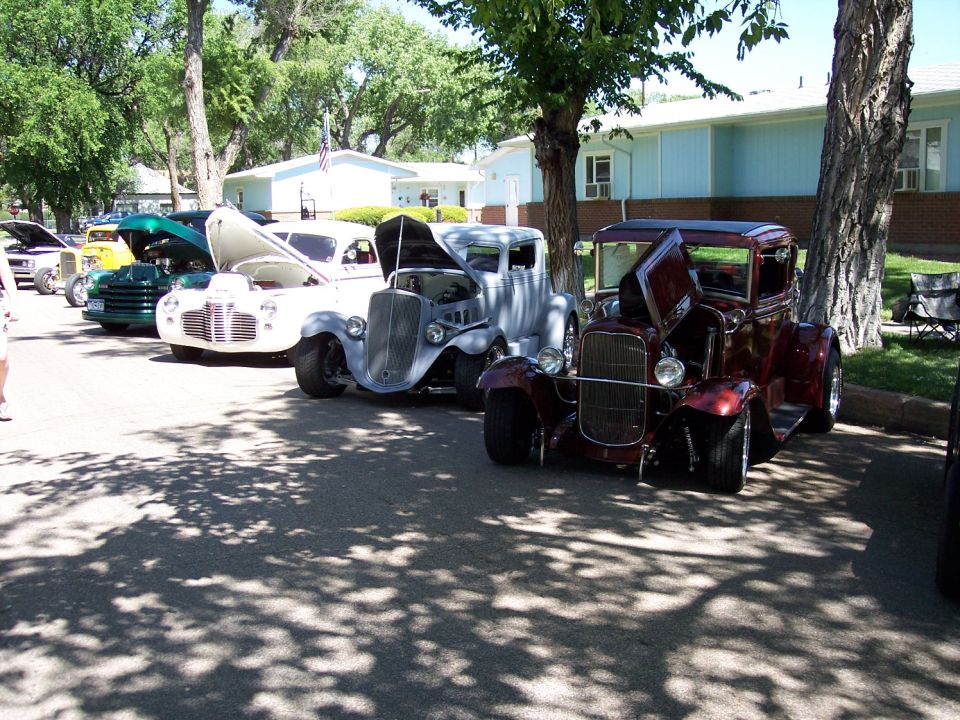 Maroon hot rod with hood open, parked in front of other classic cars