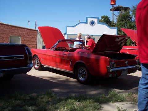 1972 Ford Ranchero - A red 1965 convertible is displayed with its hoods open, while two people examine a document.