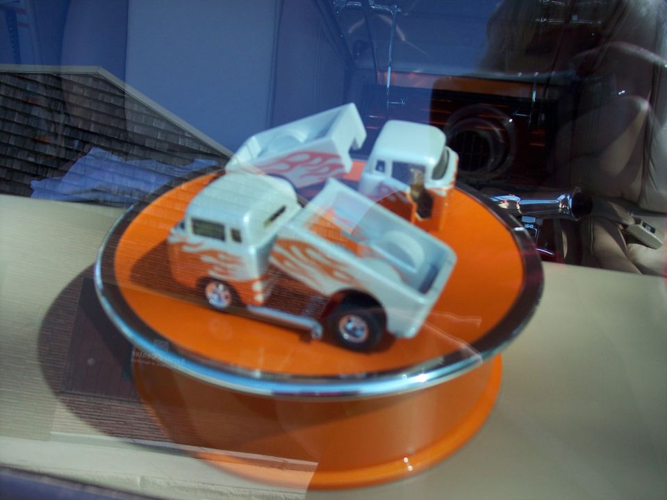 Three toy trucks with flame decals on an orange display stand
