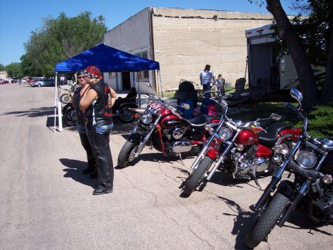1972 Ford Ranchero - People and motorcycles gathered outdoors under a tent, with a trailer in the background.