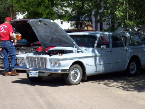 1972 Ford Ranchero - A light blue 1961 Plymouth Valiant station wagon is displayed with its hood open at a car show.