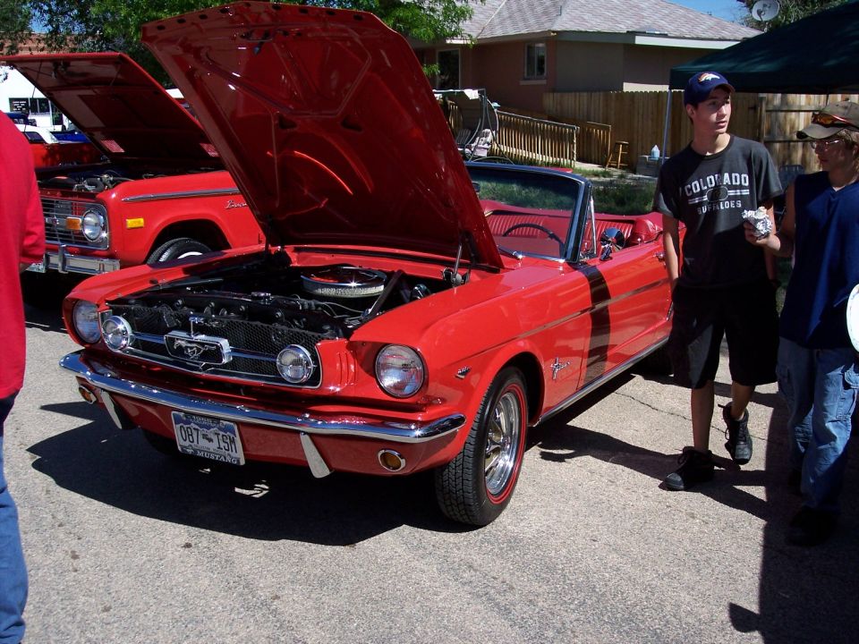 Red 1965 Ford Mustang convertible, front view, hood open. License plate reads 087-TSN
