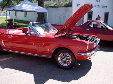 1972 Ford Ranchero - A red convertible is displayed with its hood open, parked next to another red vehicle.