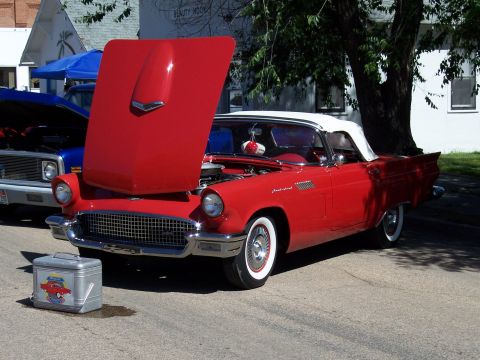 1972 Ford Ranchero - A red 1957 Ford Thunderbird convertible is displayed with its hood open, parked beside a blue truck at a car show.