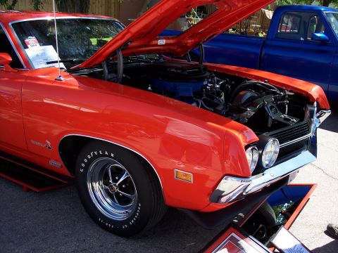 1972 Ford Ranchero - A bright orange muscle car is displayed with its hood open, revealing the engine bay.