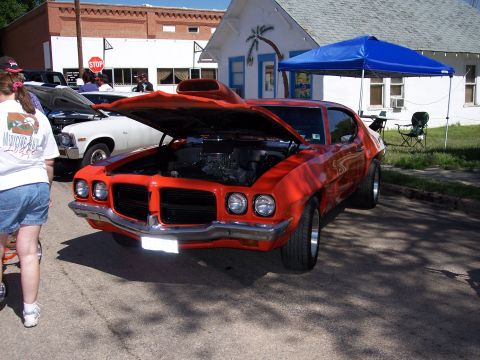 1972 Ford Ranchero - A bright orange 1972 Ford Ranchero is displayed with its hood open at a car show.
