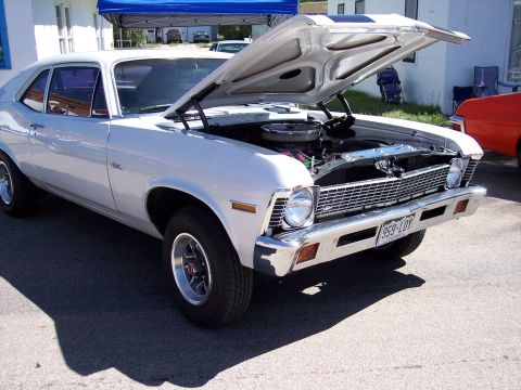 1972 Ford Ranchero - A white coupe with its hood open is parked outside, revealing its engine and racing stripes.