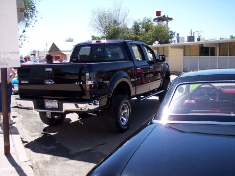 1972 Ford Ranchero - Rear view of a black Ford F-150 pickup truck, parked on a sunny day.