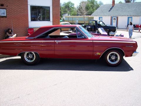 1972 Ford Ranchero - A red 1965 coupe utility vehicle is parked outside a brick building.