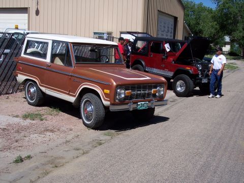 1972 Ford Ranchero - A brown 1970s Ford Bronco is parked next to a red Jeep with its hood open. A man stands by the Jeep.
