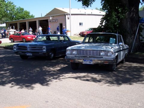 1972 Ford Ranchero - Two classic cars are parked outside a fire station on a sunny day.