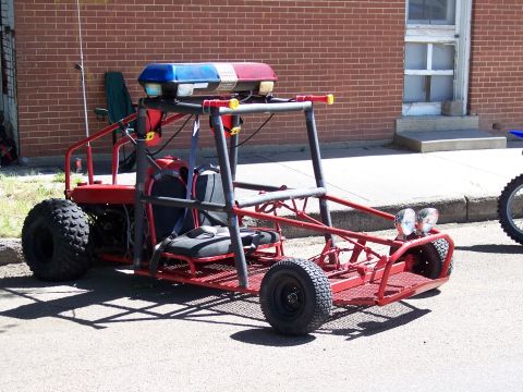 1972 Ford Ranchero - A red go-kart with a light bar and roll cage is parked on a street next to a dirt bike.