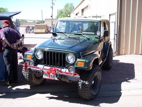 1972 Ford Ranchero - A green Jeep Wrangler is parked in front of a building with a red winch mounted on the front bumper.