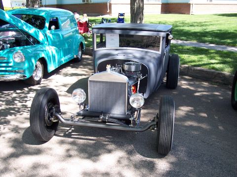 1972 Ford Ranchero - A custom hot rod is parked next to a teal panel van at an outdoor car show.