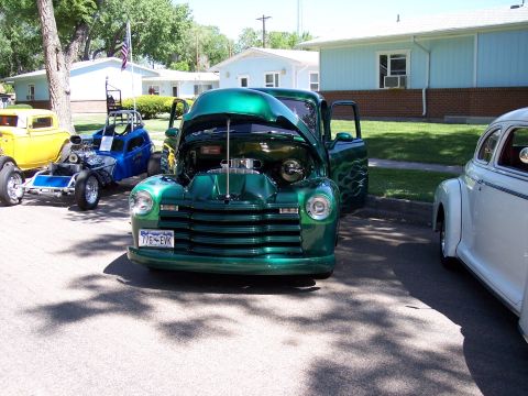 1972 Ford Ranchero - A customized green pickup truck is displayed with its hood and doors open, alongside other vehicles at an outdoor event.