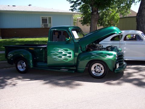 1972 Ford Ranchero - Custom green pickup truck with flame graphics and exposed engine, parked beside another vehicle.