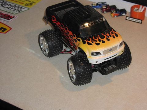 1981 Ford Bronco - A toy Ford pickup truck with flame decals sits on a table next to other small toy vehicles.