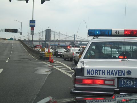 1991 Ford LTD Crown Victoria - North Haven Police sedan with lightbar sits on a bridge approach road with a large suspension bridge in the background.