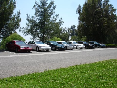 1993 Ford Taurus - Several sedans are parked in a lot, with a red 1993 Ford Taurus in the foreground.
