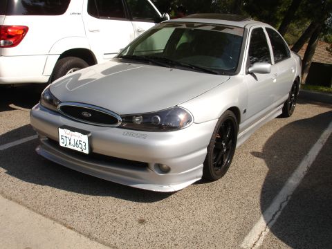 1993 Ford Taurus - Silver sedan with a custom body kit and black wheels is parked next to a white SUV.