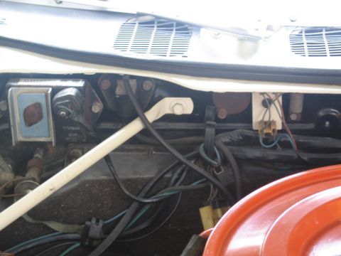 1991 Ford LTD Crown Victoria - detail of a vehicle's cowl area showing the wiper motor, linkage rod, wiring and an orange air cleaner edge below.